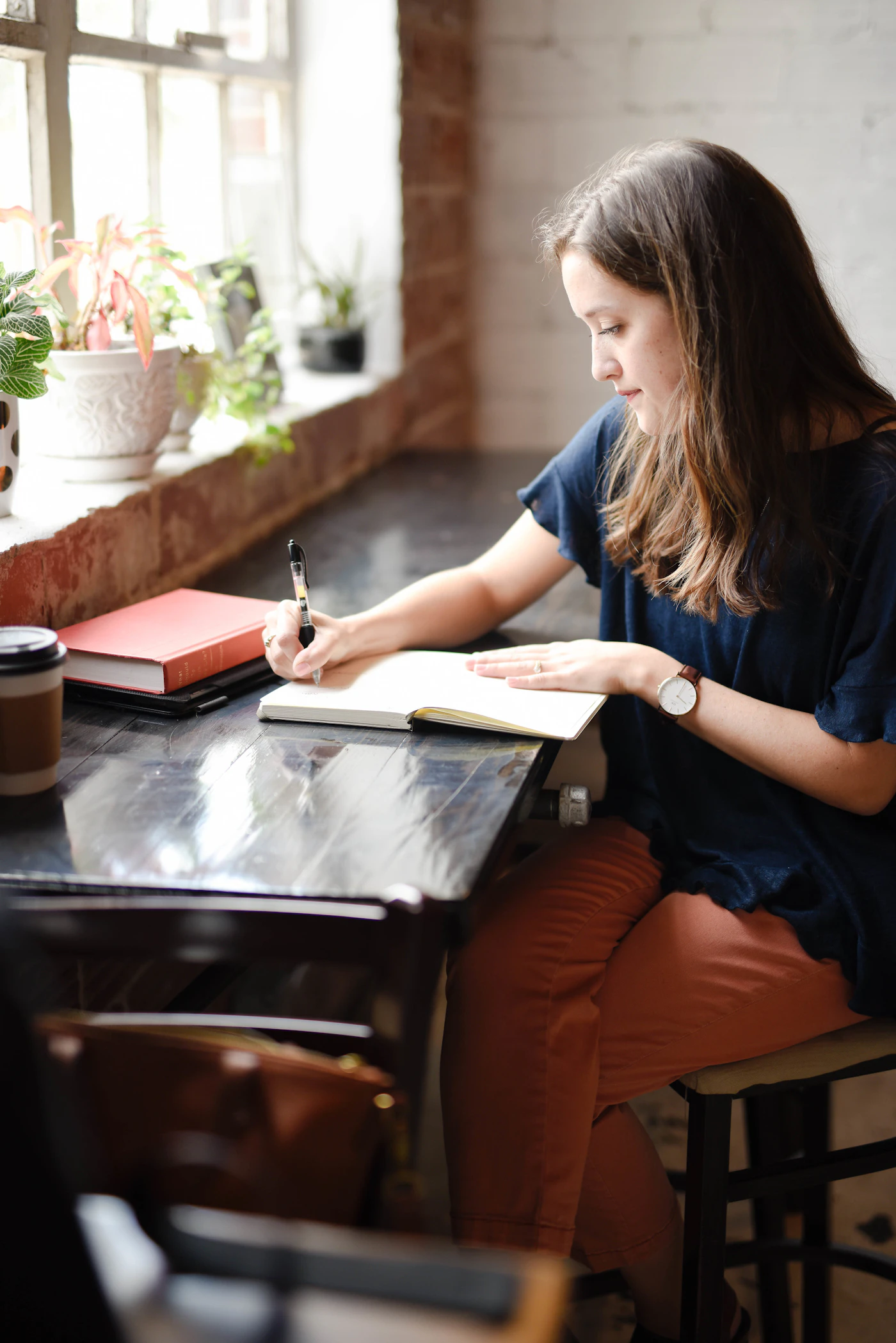 A therapist writing at a sunlit desk by a window